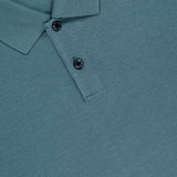 Close-up of the THEORY Goris Long Sleeve Polo Shirt in teal, made from lightweight stretch jersey with a collar and two black buttons. The Theory brand label is partially visible at the top left.