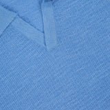 Close-up of the THEORY Brenan Knit Johnny Collar Polo Shirt in light blue, featuring a linen-blend knit with visible texture and a black THEORY label in size M.