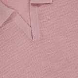 Close-up of the Brenan Knit Johnny Collar Polo Shirt by THEORY in light pink, featuring a textured knit and V-neck Johnny collar with an open neckline displaying the black THEORY label.