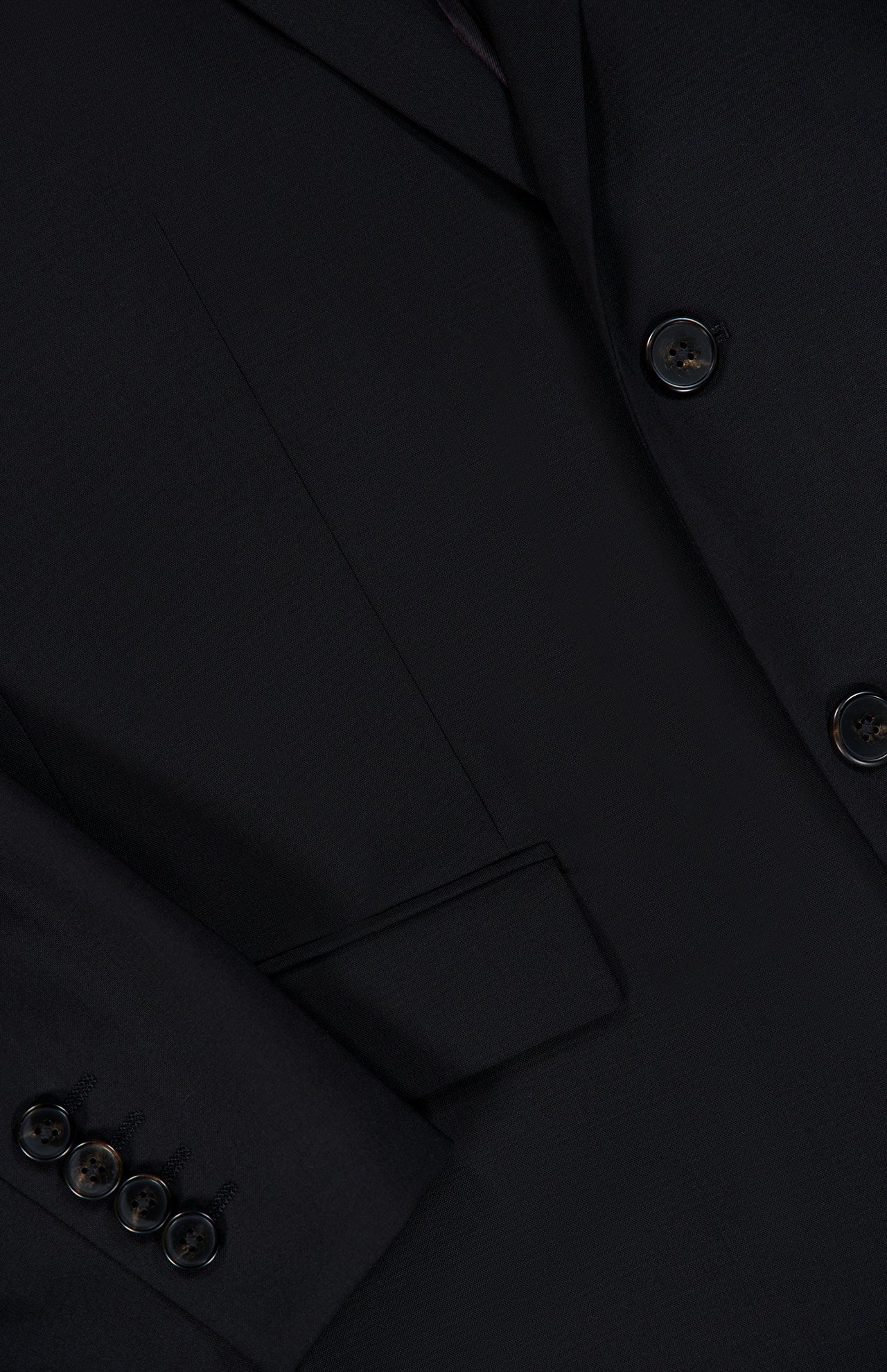 Close-up of the THEORY Chambers Blazer in Stretch Wool, featuring black buttons on the sleeve, a flap-front pocket, and meticulously stitched seams. The smooth virgin wool fabric is finely tailored for a polished finish.