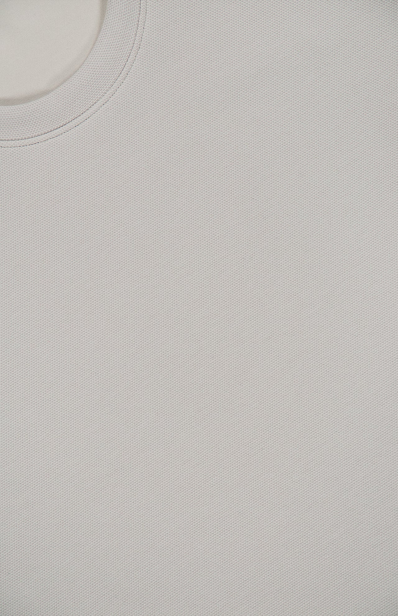 Close-up of the THEORY Delroy Cotton-blend T-Shirt in a plain, light gray stone color, highlighting its textured double pique jersey fabric. The upper left corner shows part of the round neckline, with the comfortable weave and material details of this t-shirt clearly visible.