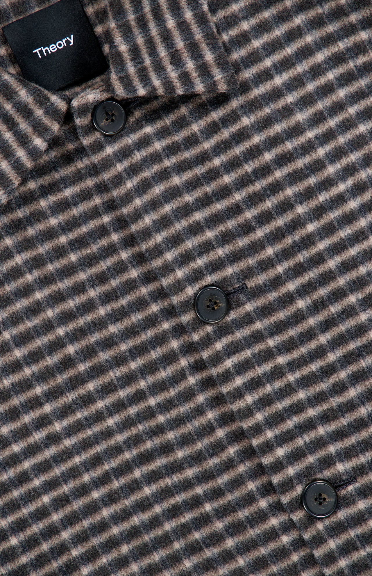 Close-up of the Double Face Wool Short Jacket by THEORY, a men’s outerwear piece in dark brown featuring a classic wool check pattern in brown and gray tones, finished with black buttons and a visible black THEORY label on the collar.