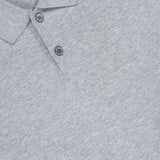 Close-up of the THEORY Goris Long Sleeve Polo Sweater in light gray, featuring a classic collar with two buttons. The soft knit fabric gives it a sweater-like appearance, and a black THEORY label with white text is partially visible at the neckline.