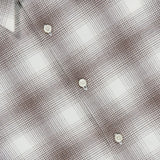 Close-up of the THEORY Irving Faded Plaid Shirt, featuring a gray and white checkered pattern. The shirt includes white buttons, a visible collar, and subtly textured grid detailing in the fabric.