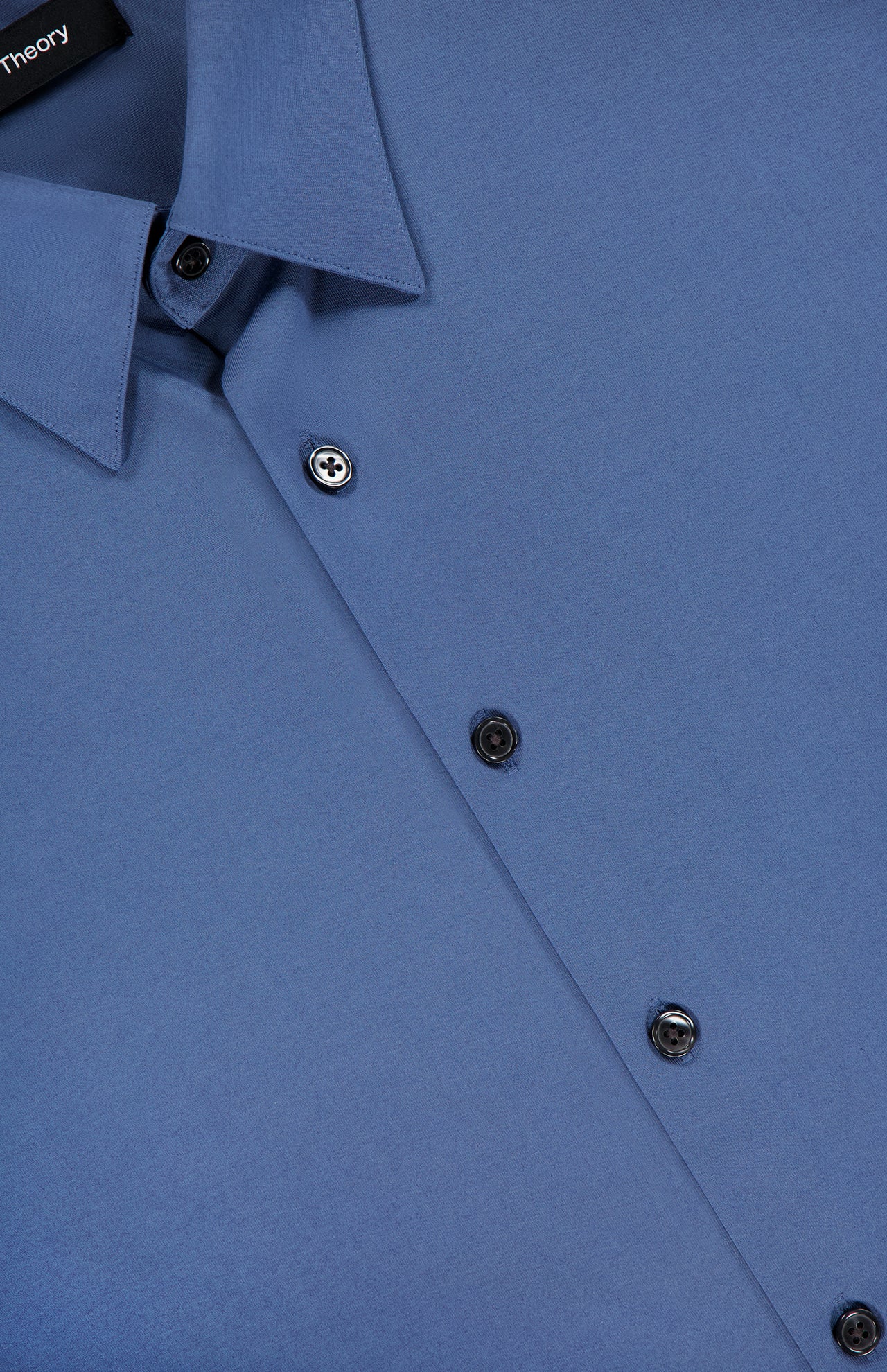 Close-up of the THEORY Irving Short Sleeve Structure Shirt in cornflower blue, folded neatly. Features black buttons, visible collar and front, and an inner brand tag—ideal for a polished, wrinkle-free look.