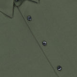 Close-up view of the Irving Short Sleeve Structure Shirt in wrinkle-free olive green, featuring dark buttons and a pointed collar. A black label with the brand name THEORY is visible inside the collar.