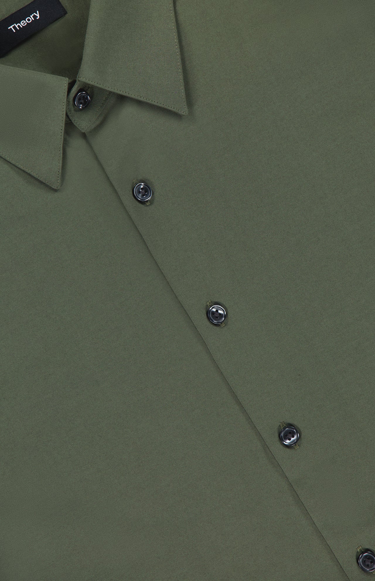 Close-up view of the Irving Short Sleeve Structure Shirt in wrinkle-free olive green, featuring dark buttons and a pointed collar. A black label with the brand name THEORY is visible inside the collar.