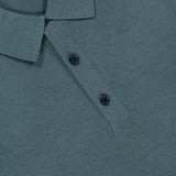 Close-up of a textured, muted dark green Silk Cotton Polo Shirt by THEORY, featuring a collar, two-button front placket, and visible brand label inside the neckline.