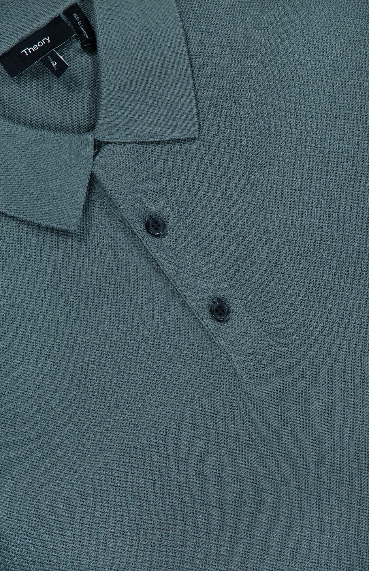 Close-up of a textured, muted dark green Silk Cotton Polo Shirt by THEORY, featuring a collar, two-button front placket, and visible brand label inside the neckline.
