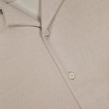 Close-up of the Soft Terry Short Sleeve Shirt by THEORY, in beige with a textured finish, pointed collar, and three white buttons. This casual work shirt exemplifies refined style and effortless sophistication.