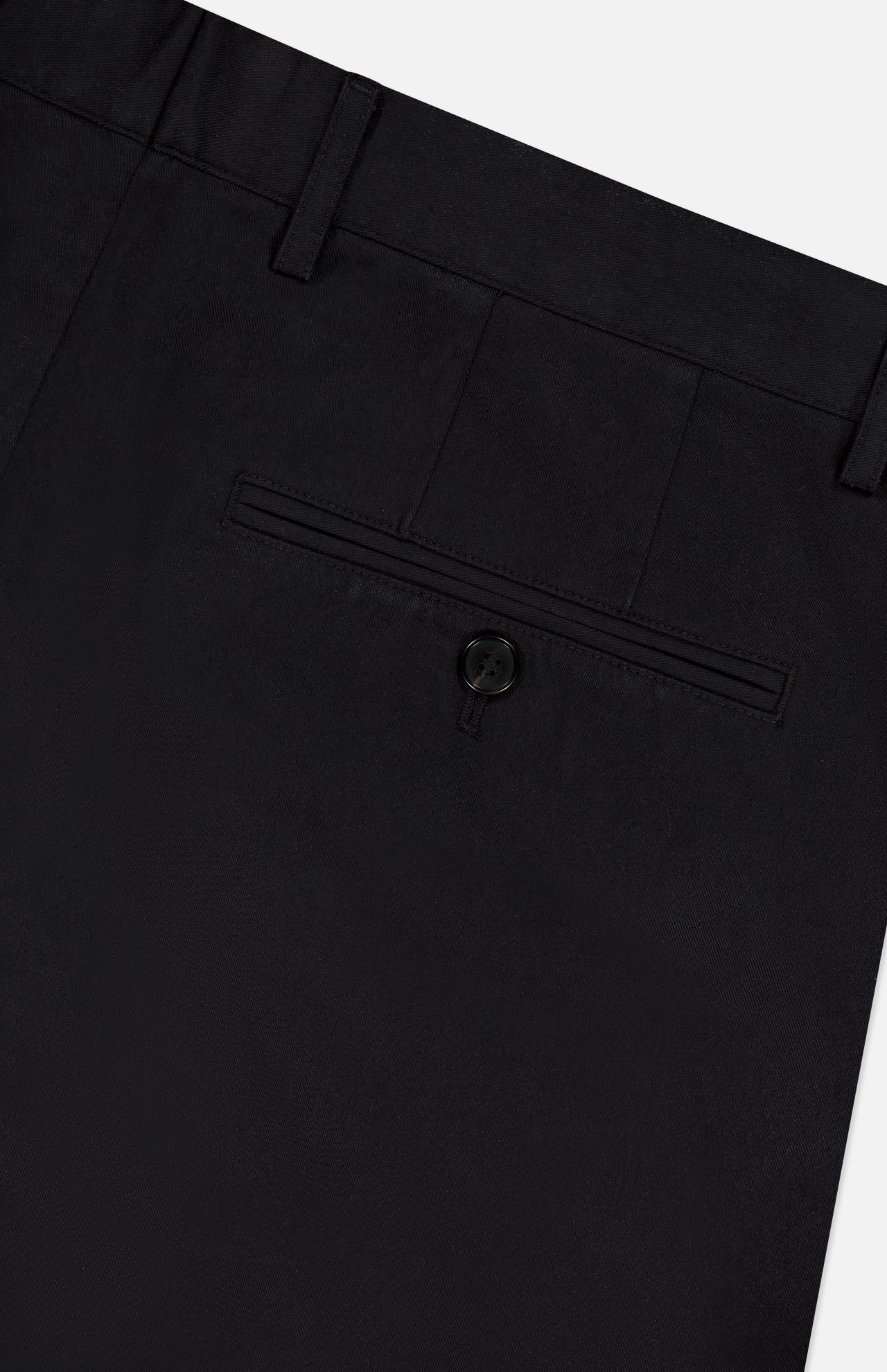 Close-up of the back of THEORY Standard Chino Moons Shorts, showing a single buttoned welt pocket, belt loops, and part of the waistband in black cotton twill against a light background.