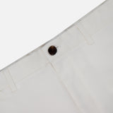 A close-up of the waistband and upper section of THEORY Standard Chino Moons Shorts in white cotton twill, highlighting a dark brown button, belt loops, and part of a front pocket against a plain background.