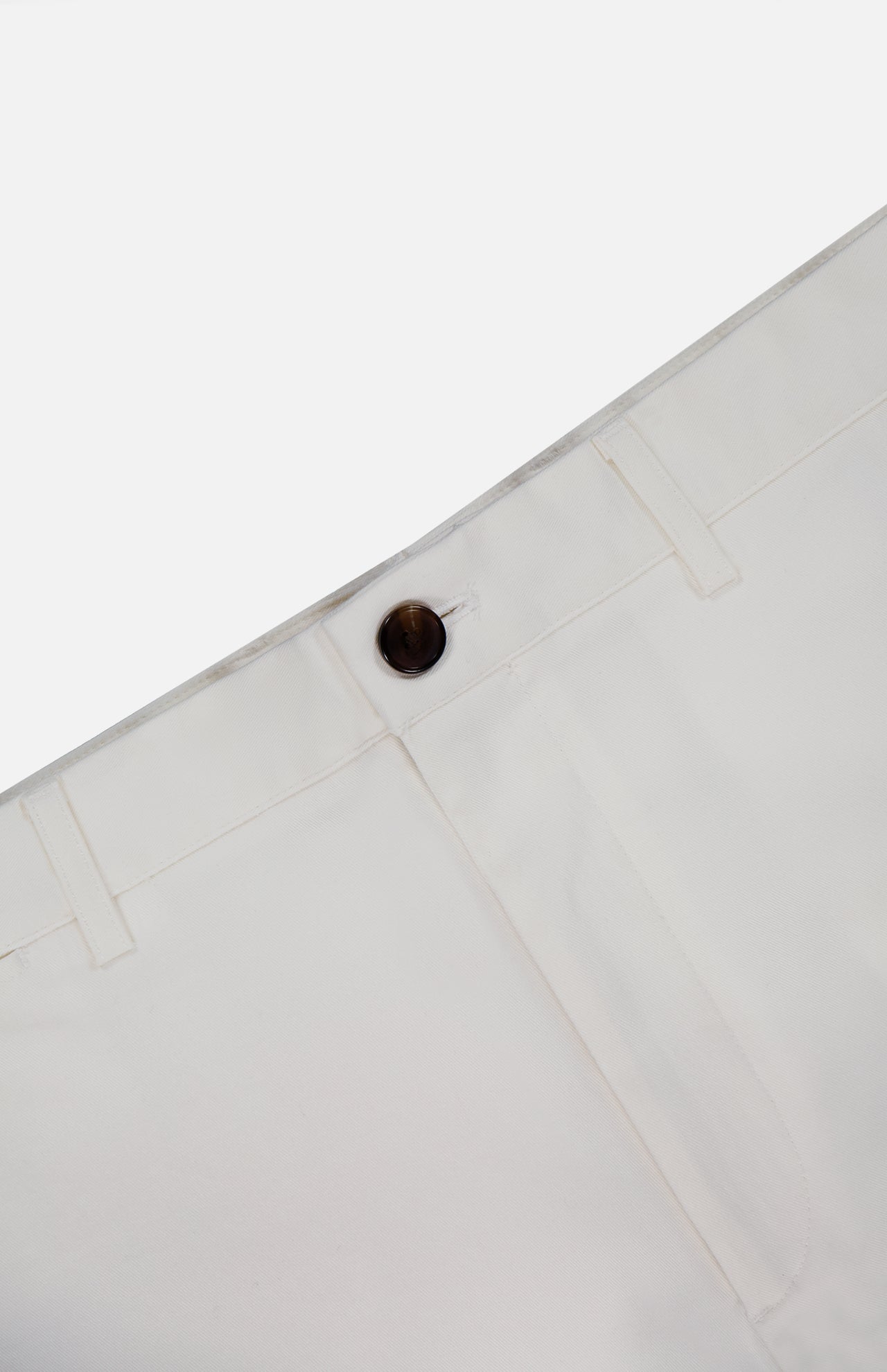 A close-up of the waistband and upper section of THEORY Standard Chino Moons Shorts in white cotton twill, highlighting a dark brown button, belt loops, and part of a front pocket against a plain background.
