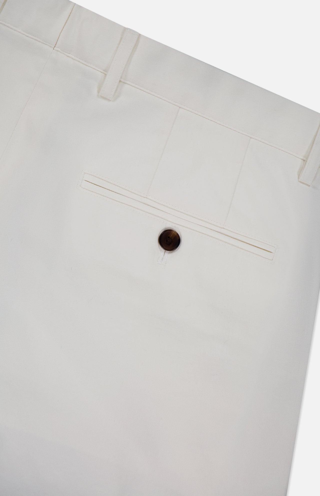 Close-up of the back pocket of THEORY's Standard Chino Moons Shorts, featuring white cotton twill fabric, a single brown button, and belt loops at the waistband.