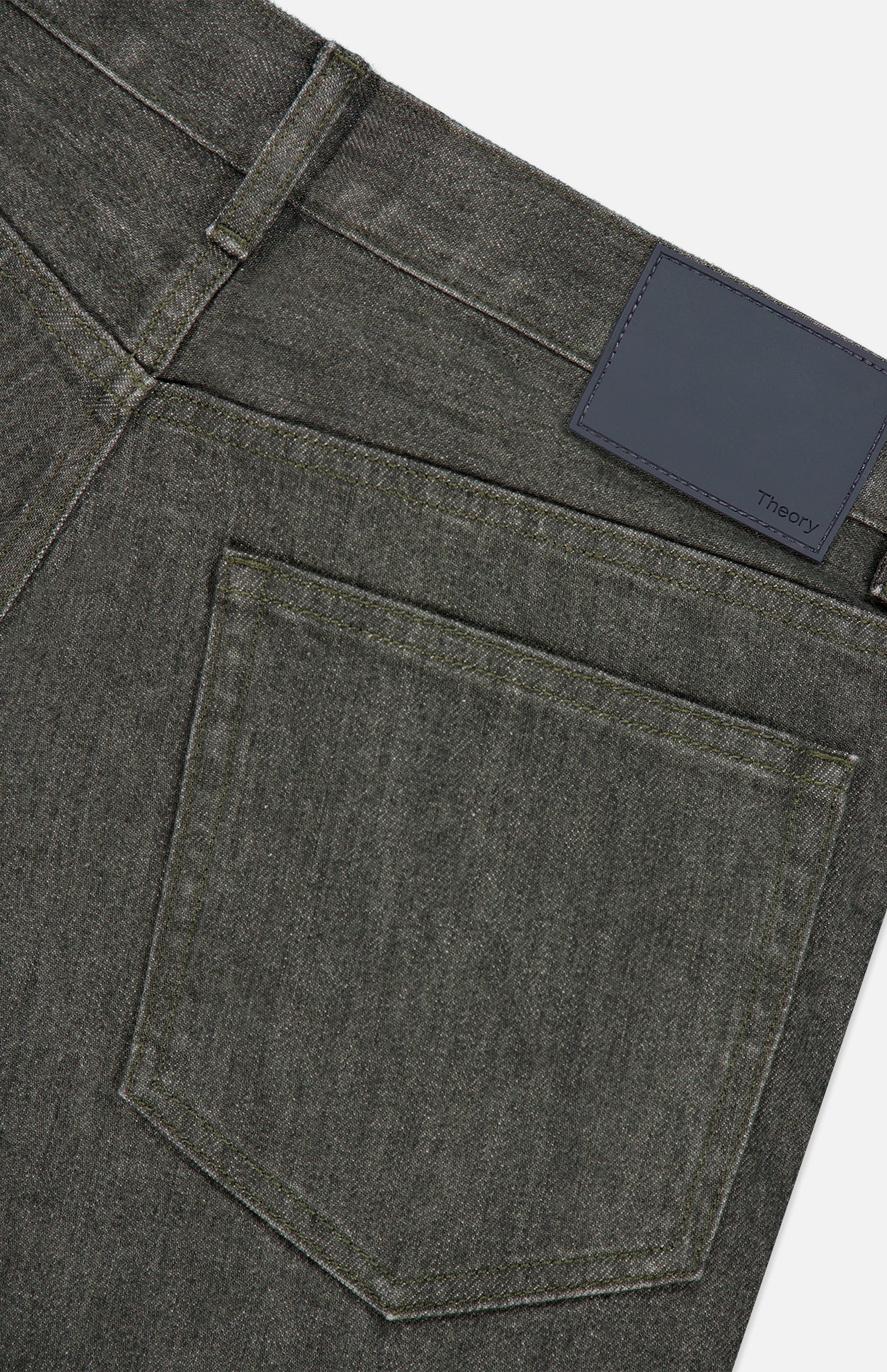 Close-up of the back pocket and waistband of dark gray, stretch-cotton Standard 5-Pocket Jeans by THEORY, featuring a black leather patch with the brand name in small text. The denim has a subtle texture and a classic five-pocket design.