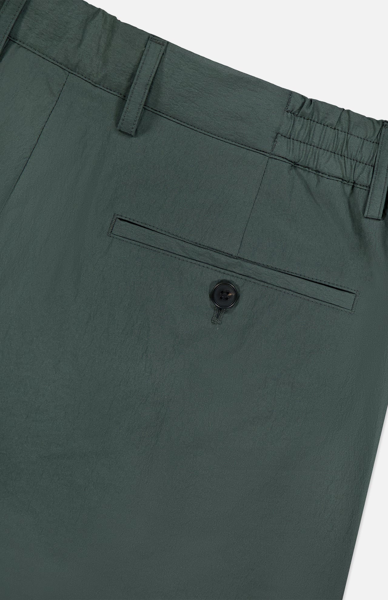 Close-up of the waist and back pocket of THEORY Standard Nylon Drawstring Trouser Pants in dark green, featuring an elasticized waist with belt loops and a single back pocket secured by a black button.