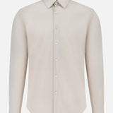 The Sylvain Structure Dress Shirt by THEORY is a light beige, long-sleeve shirt featuring a classic collar and button-down front. Crafted from wrinkle-resistant fabric, this machine-washable dress shirt offers effortless style without visible pockets and is presented on a plain white background.