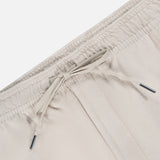 Close-up of the waistband of THEORY Terry Drawstring Shorts in light beige, featuring an elastic band and adjustable drawstring with metal tips, shown against a plain white background.