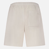Back view of THEORY Terry Drawstring Shorts in a relaxed beige fit, featuring an adjustable drawstring waist and a single right patch pocket, shown against a plain white background.