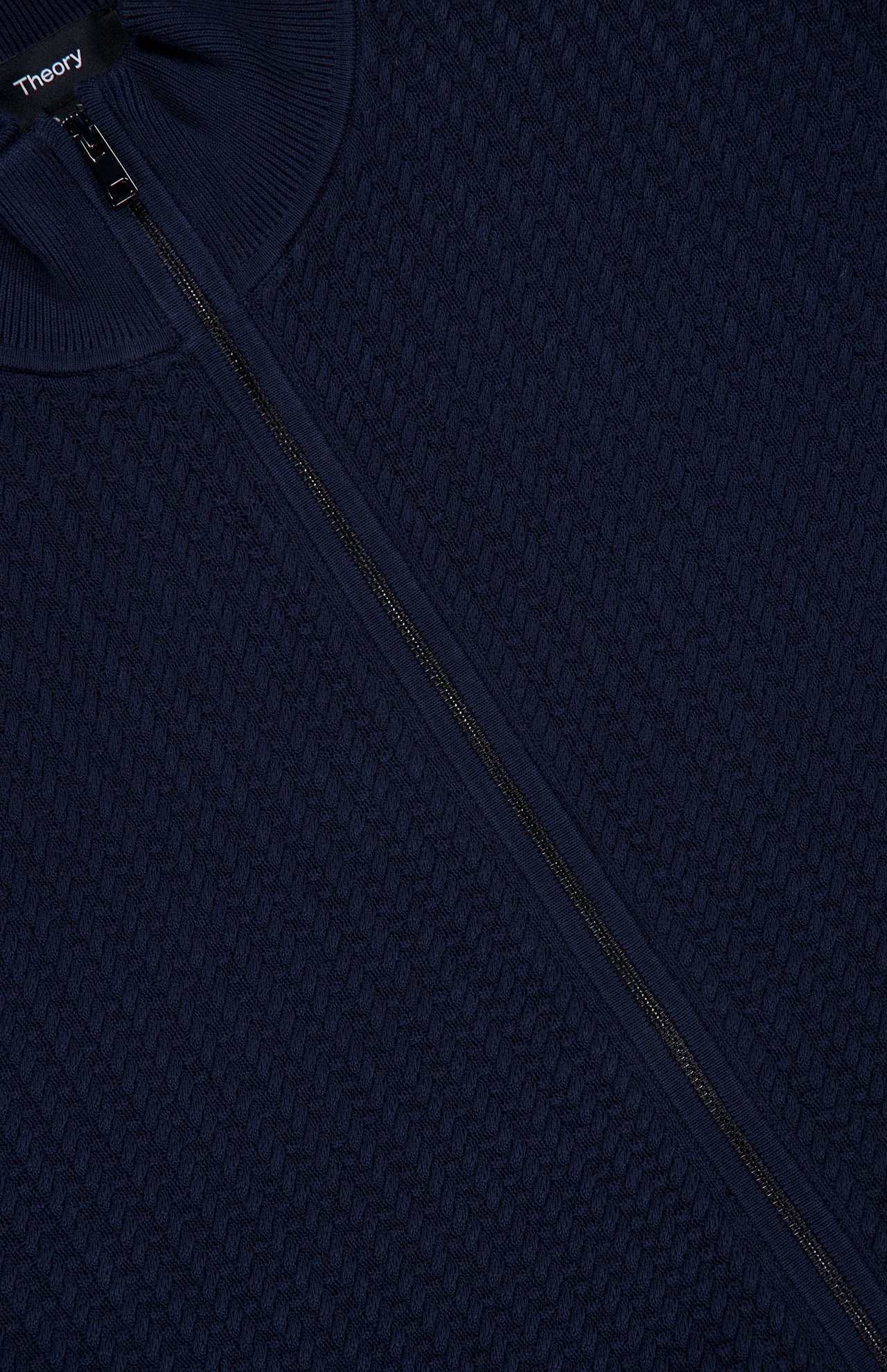 Close-up of the Walton Full Zip Sweater in navy blue, featuring a textured knit, visible full-length zipper, and ribbed mock collar, with the THEORY brand label displayed at the neckline.