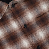 Close-up of the THEORY Wool Plaid Button Down Shirt, featuring brown and beige plaid fabric, black buttons, and a visible brand label at the collar.