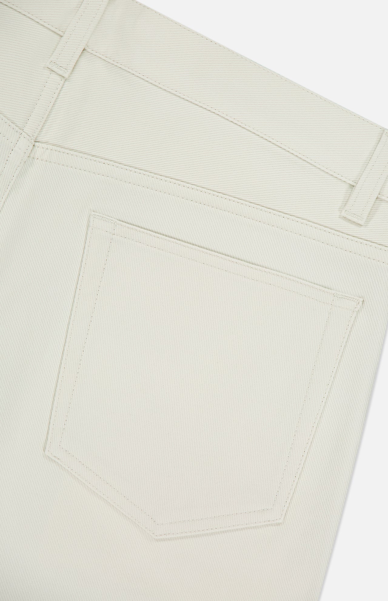Close-up of the back pocket on THEORY Raffi Stretch Twill Pants in an oat milk shade, showing detailed stitching and the texture of their 4-way stretch fabric.