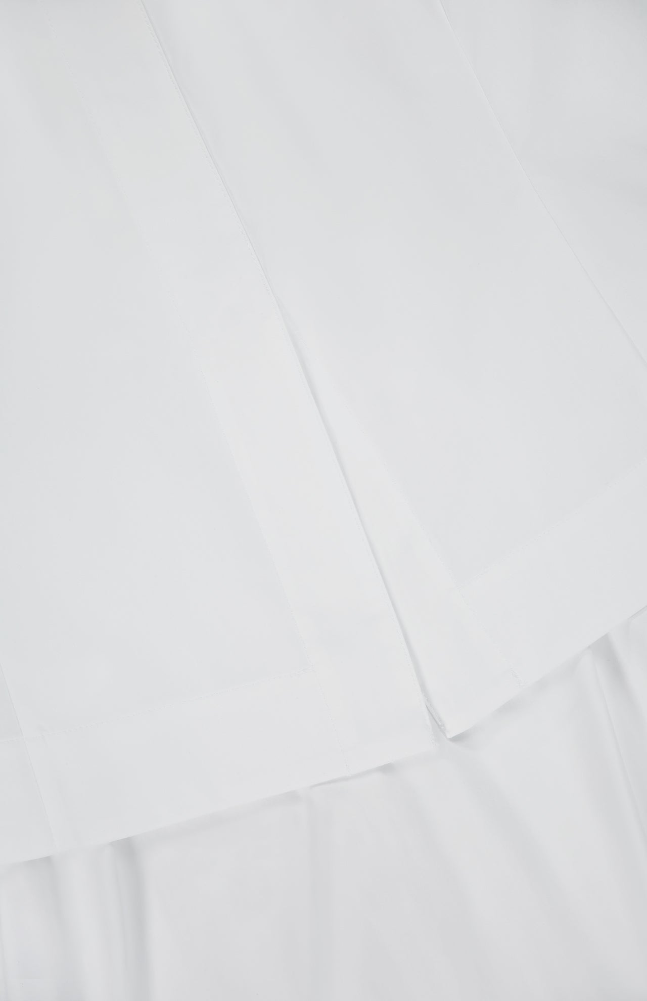 A close-up of crisp, white fabric with clean seams and overlapping layers, evoking the neatly tailored Boatneck Set Midi Dress by THEORY.
