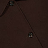 Close-up of the Boxy Cuff Jacket by THEORY in chocolate brown wool-blend, featuring two dark buttons, a pointed collar, and part of a black label with white text. The soft, smooth fabric hints at the jacket’s modern boxy fit and stylish design.