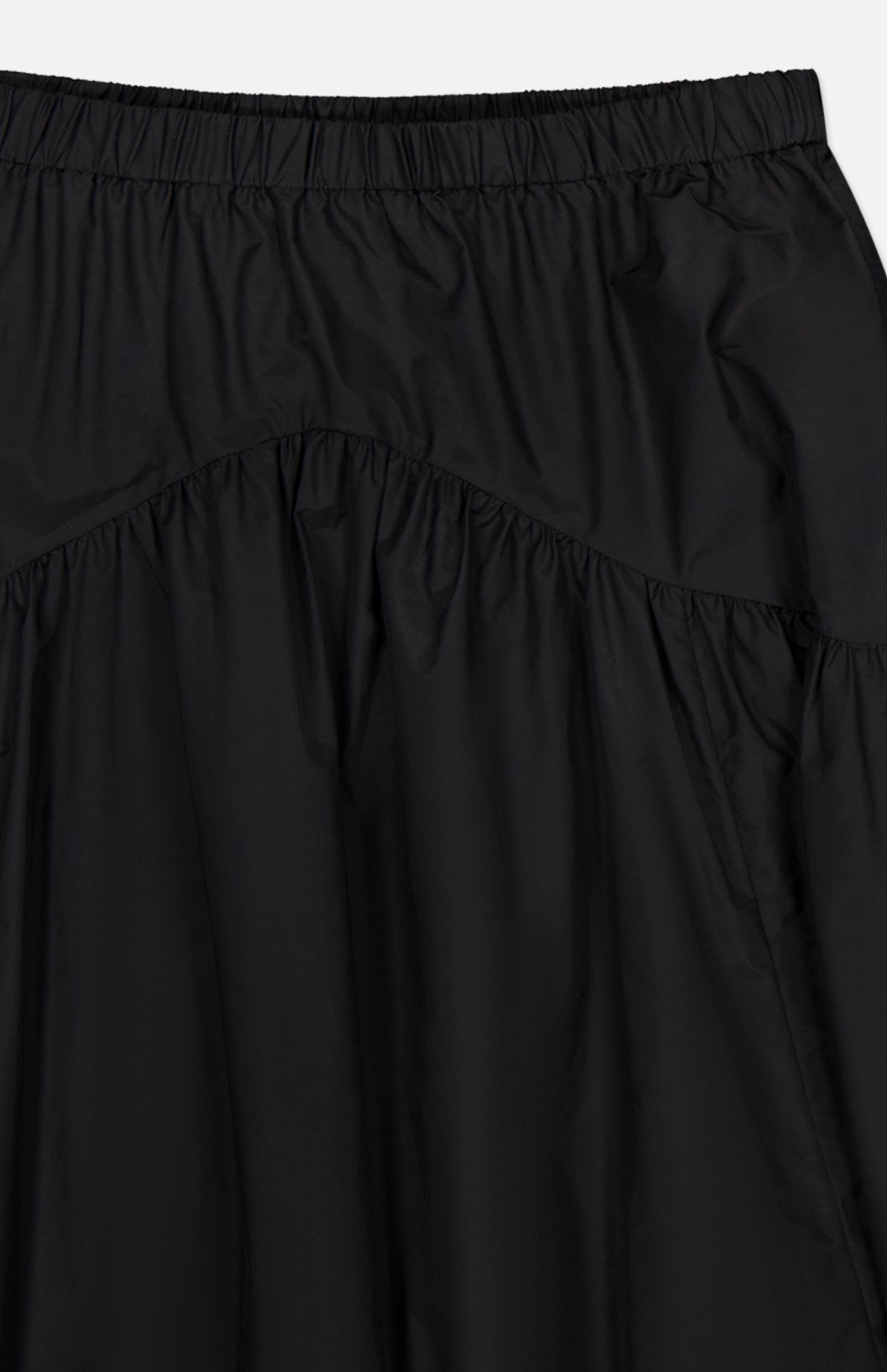 Close-up of the THEORY Curved Yoke Circle Skirt in black, crafted from lightweight, slightly shiny fabric with a pull-on elastic waistband and gathered detail below a curved seam.