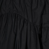 Close-up of THEORY’s Curved Yoke Circle Skirt in black, showcasing a pull-on style with an elastic waistband. Gathered, lightweight fabric and diagonal seams create a ruffled, textured effect with a subtle sheen.