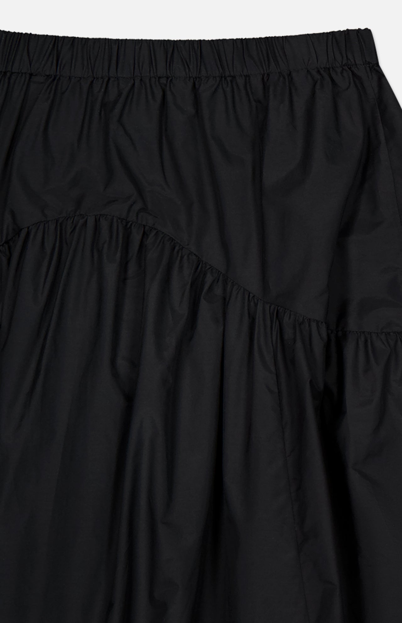 Close-up of THEORY’s Curved Yoke Circle Skirt in black, showcasing a pull-on style with an elastic waistband. Gathered, lightweight fabric and diagonal seams create a ruffled, textured effect with a subtle sheen.