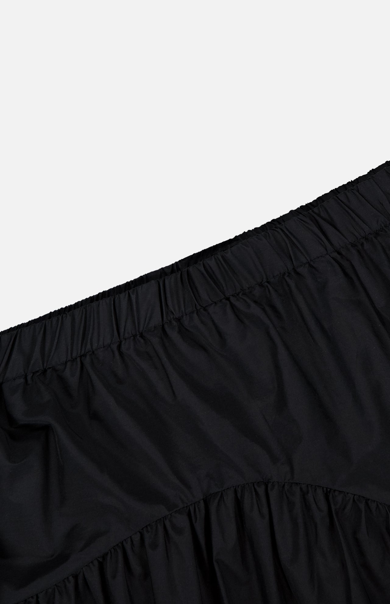 Close-up of the THEORY Curved Yoke Circle Skirt in black, featuring a gathered fabric and elastic waistband for an easy pull-on style, shown against a plain white background.
