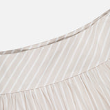 Close-up of THEORY's Front Vented Volume Striped Skirt—a beige and white cotton-blend A-line midi featuring diagonal neutral stripes and gathered pleats near the seam.