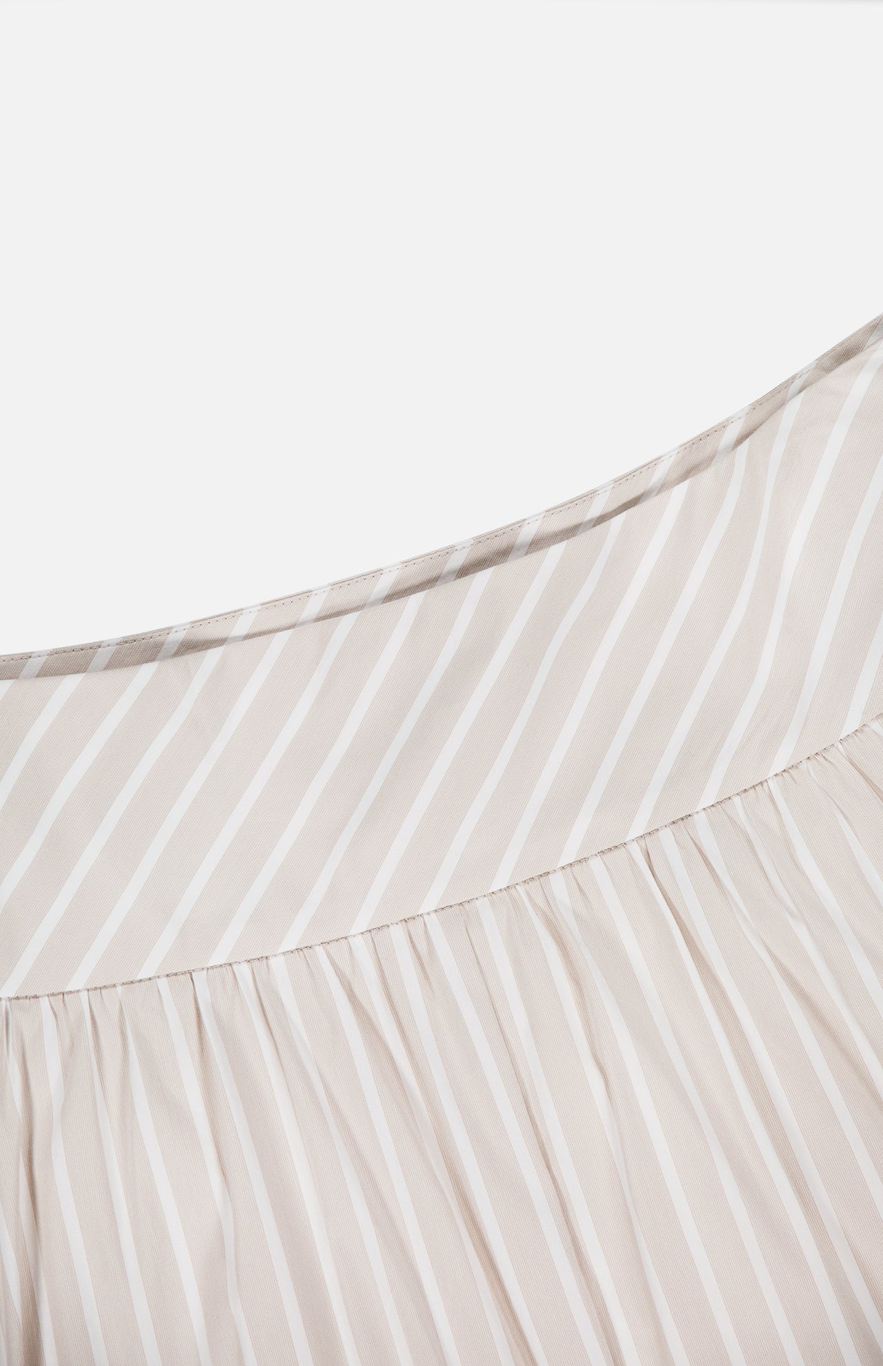 Close-up of THEORY's Front Vented Volume Striped Skirt—a beige and white cotton-blend A-line midi featuring diagonal neutral stripes and gathered pleats near the seam.