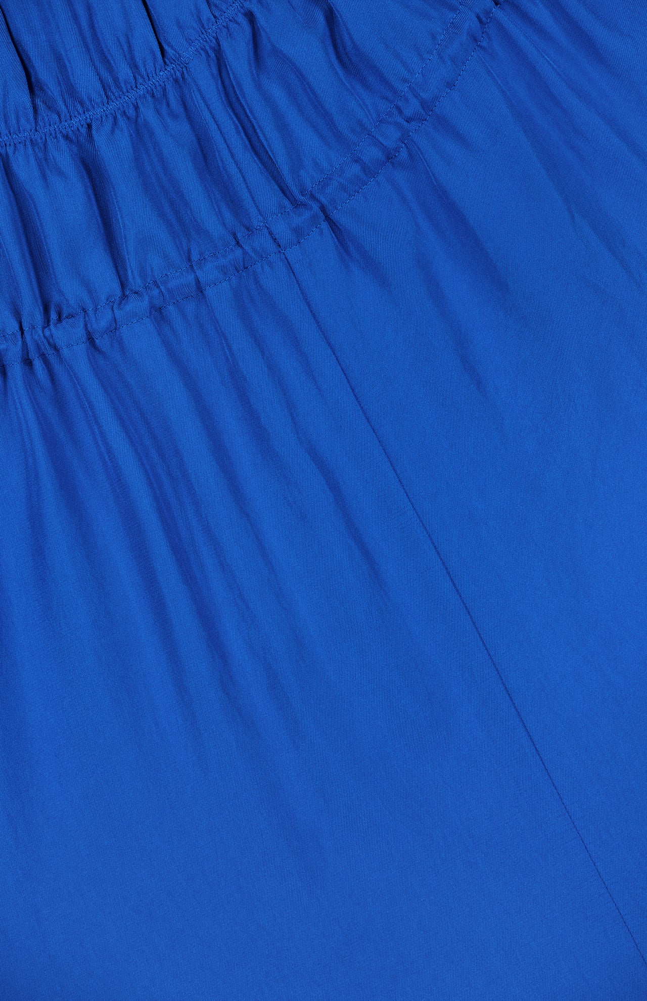 Close-up of the Gathered V-Neck Dress by THEORY in electric blue, featuring gathered elastic stitching near the top that creates soft vertical folds and a slightly textured, wrinkled appearance. The stretchy elastic waistband ensures enhanced comfort and fit.