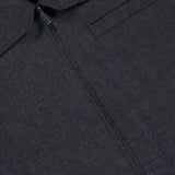 Close-up of the Harrington Cropped Jacket by THEORY in dark gray charcoal. This stylish wool-blend piece features a zip-up front, chest pocket, and two metal buttons near the collar. The visible fabric texture and part of the THEORY brand label highlight its sophisticated design—making it perfect as an office jacket or for elevating everyday outfits.