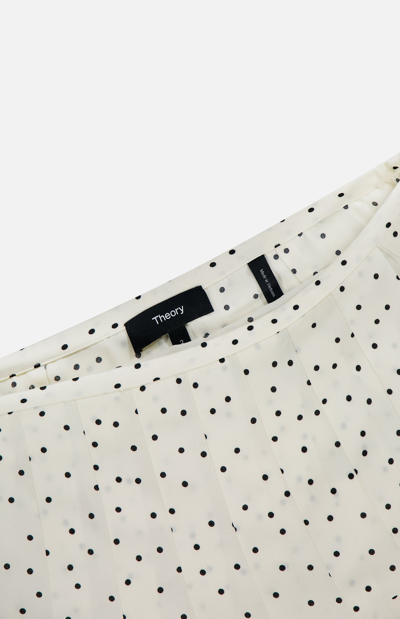 Close-up of the Pleated Polka Dot Wrap Skirt by THEORY, featuring a stylish pleated design and bold black polka dots—a chic piece for a polished office look.