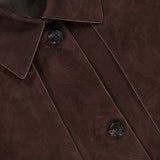Close-up of the Reece Cropped Trench Coat by THEORY in chocolate brown suede, featuring large lapels, two dark buttons, and visible stitching. A small black THEORY tag is partially visible at the top left.