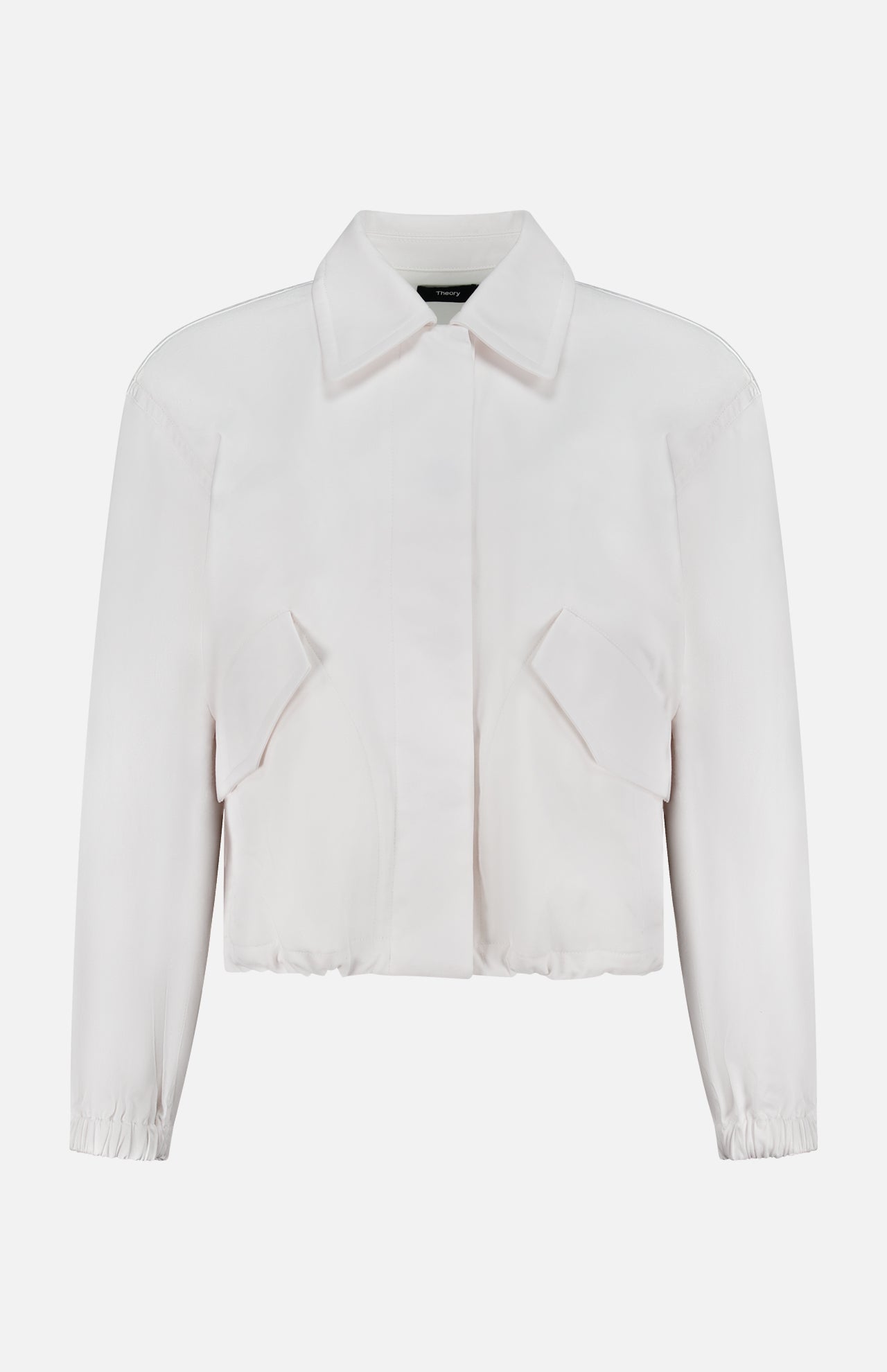The THEORY Relaxed Flyer Jacket is a white, long-sleeve, collared cotton-blend piece with a cropped fit, front flap pockets, and elasticated cuffs, providing lightweight warmth and shown against a plain white background.