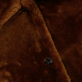 Close-up of a brown Theory Reversible Shearling Trench Coat featuring a collar and a visible button.