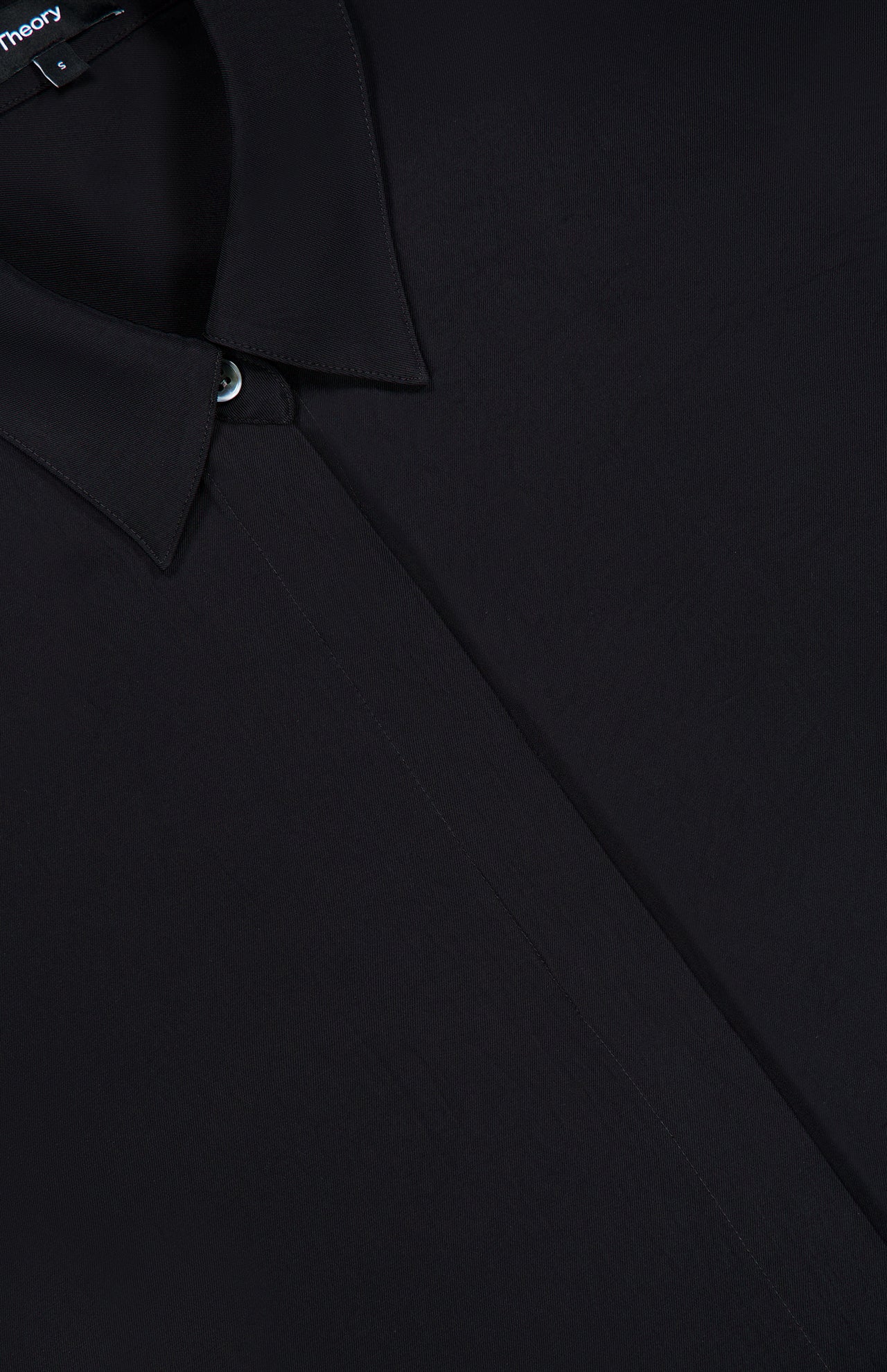 Close-up of the THEORY Short Sleeve Belted A-Line Dress in black, highlighting the refined collar stitching, top button detail, and smooth fabric texture—evoking an air of timeless sophistication.