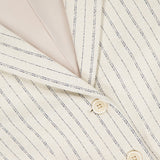 Close-up of the THEORY Shrunken 3 Button Jacket in cream crepe with thin black stripes, featuring two beige buttons and an inner THEORY label.
