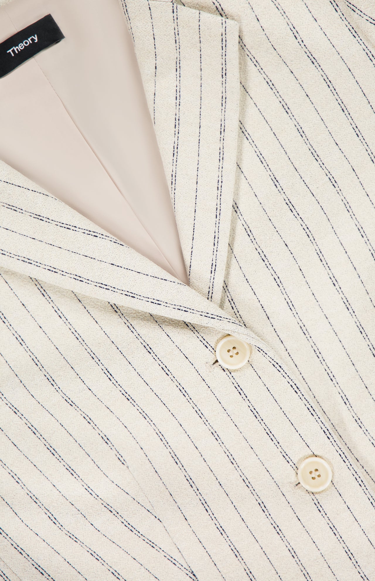Close-up of the THEORY Shrunken 3 Button Jacket in cream crepe with thin black stripes, featuring two beige buttons and an inner THEORY label.