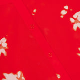 Close-up of the THEORY Sleeveless Abstract Floral Shell Top, featuring bright red fabric with white abstract floral patterns and a row of small, round buttons down the center. The material appears light and slightly sheer.