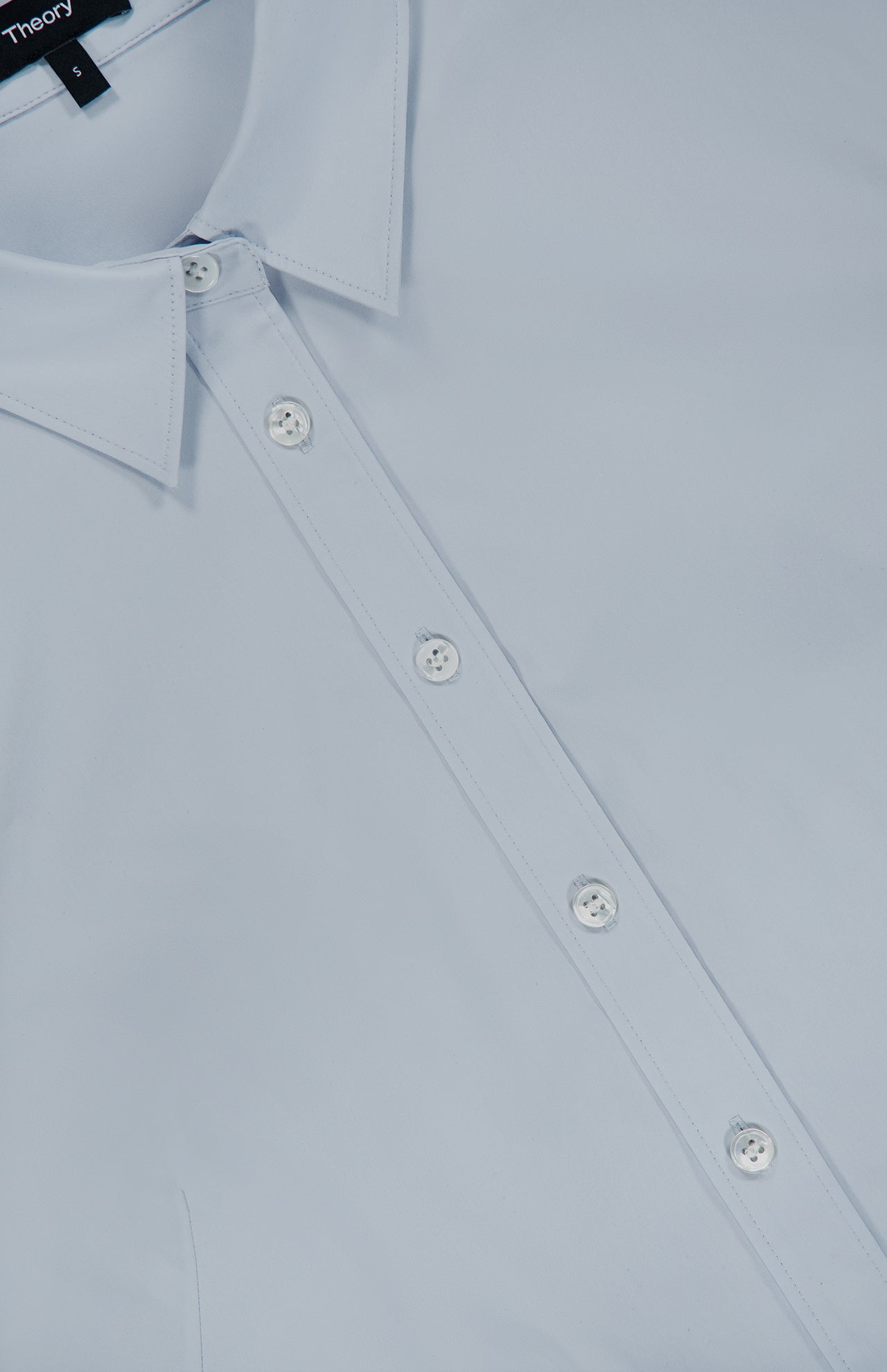 Close-up of the THEORY Tailored Cutaway Shirt in light blue, a slim-fit button-up featuring white buttons, a pointed collar, and a subtle cutaway hem, shown laying flat.