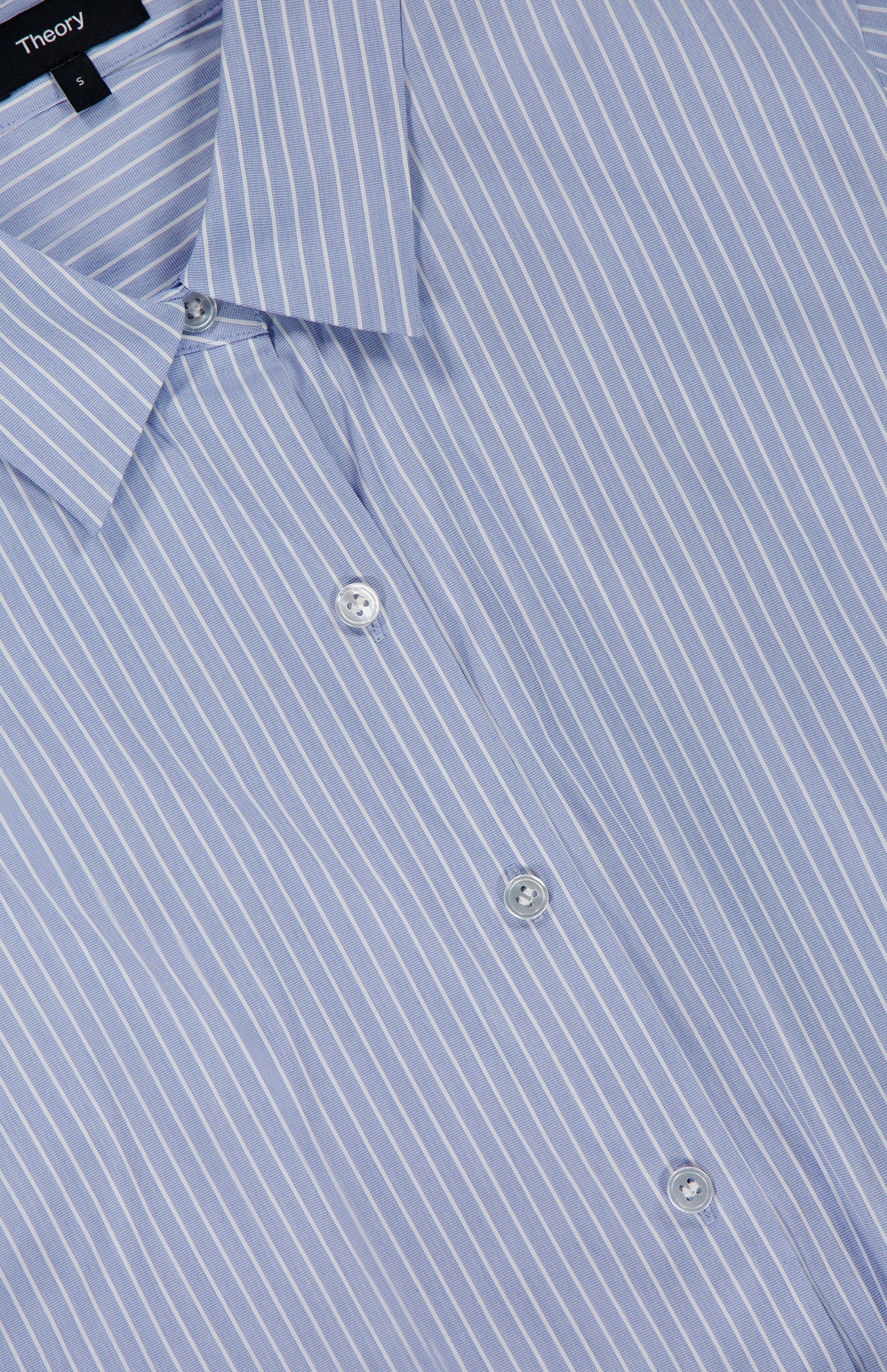 Close-up of the Tie Front Striped Short Sleeve Blouse by THEORY, featuring blue fabric with crisp white vertical stripes, a classic collar, three visible buttons, and a label at the neckline for a contemporary take on the timeless button-up style.