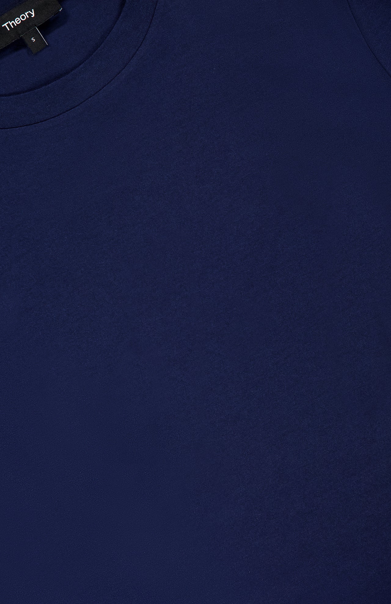 Close-up view of the Tiny Cotton T-shirt by THEORY, crafted from soft Pima cotton in plain navy blue. This style features a crew neckline and a small black brand tag at the collar, while its fitted silhouette elevates its modern look.