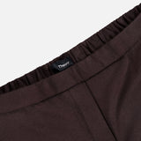 Close-up of the waistband of a pair of chocolate brown Treeca Pull-On Pants with an elastic waist and a THEORY brand tag visible at the center. The background is plain white, highlighting these stylish slim fit wool pants—perfect for sophisticated office attire.