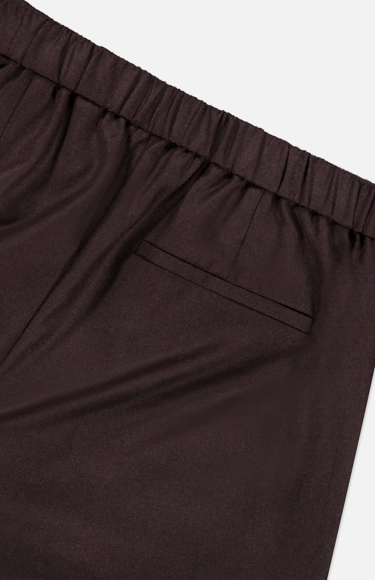 Close-up of the THEORY Treeca Pull-On Pant in chocolate brown, featuring an elastic waistband and a single welt back pocket, displayed against a white background.
