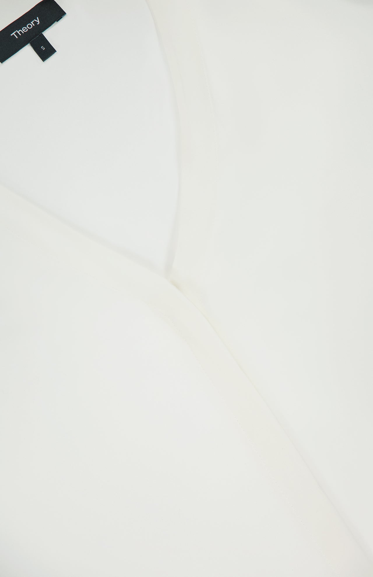 Close-up of an off-white Volume Sleeve Silk Blouse from THEORY, showing the V-neckline, part of the collar, and a black label with the brand name THEORY and size 4.